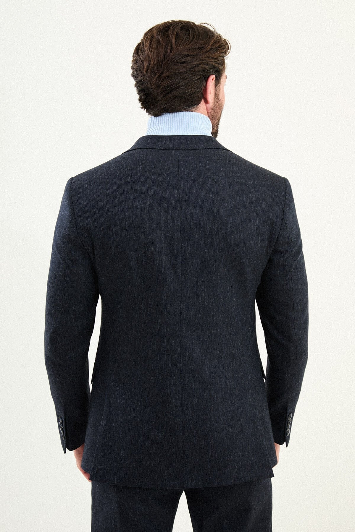 Men’s matte navy blue slim-fit single-breasted wool-blend suit with notch lapels and two-button closure, high-wool fabric with stretch for wrinkle-resistant winter wear, styled with a light blue turtleneck.